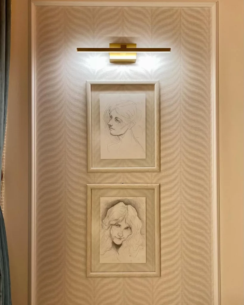 Quadros em destaque por meio da luz fria e direta na parede de casa. Os desenhos são de mulheres jovens e traços finos de grafite.
