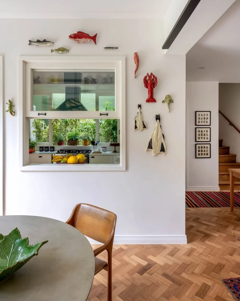 Parede decorada com esculturas de animais aquáticos em estilo praiano e tem uma mesa de madeira com cadeira.