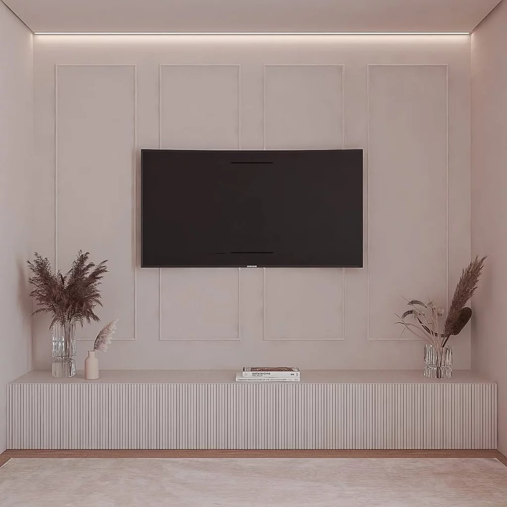 Parede com boiserie na sala de televisão, com cores neutras e vasos de flores secas adornando o aparador