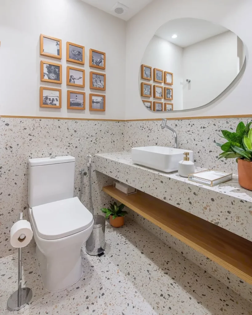 Lavabo com galeria de fotos em quadros pequenos, espelho orgânico e prateleira abaixo da pia.