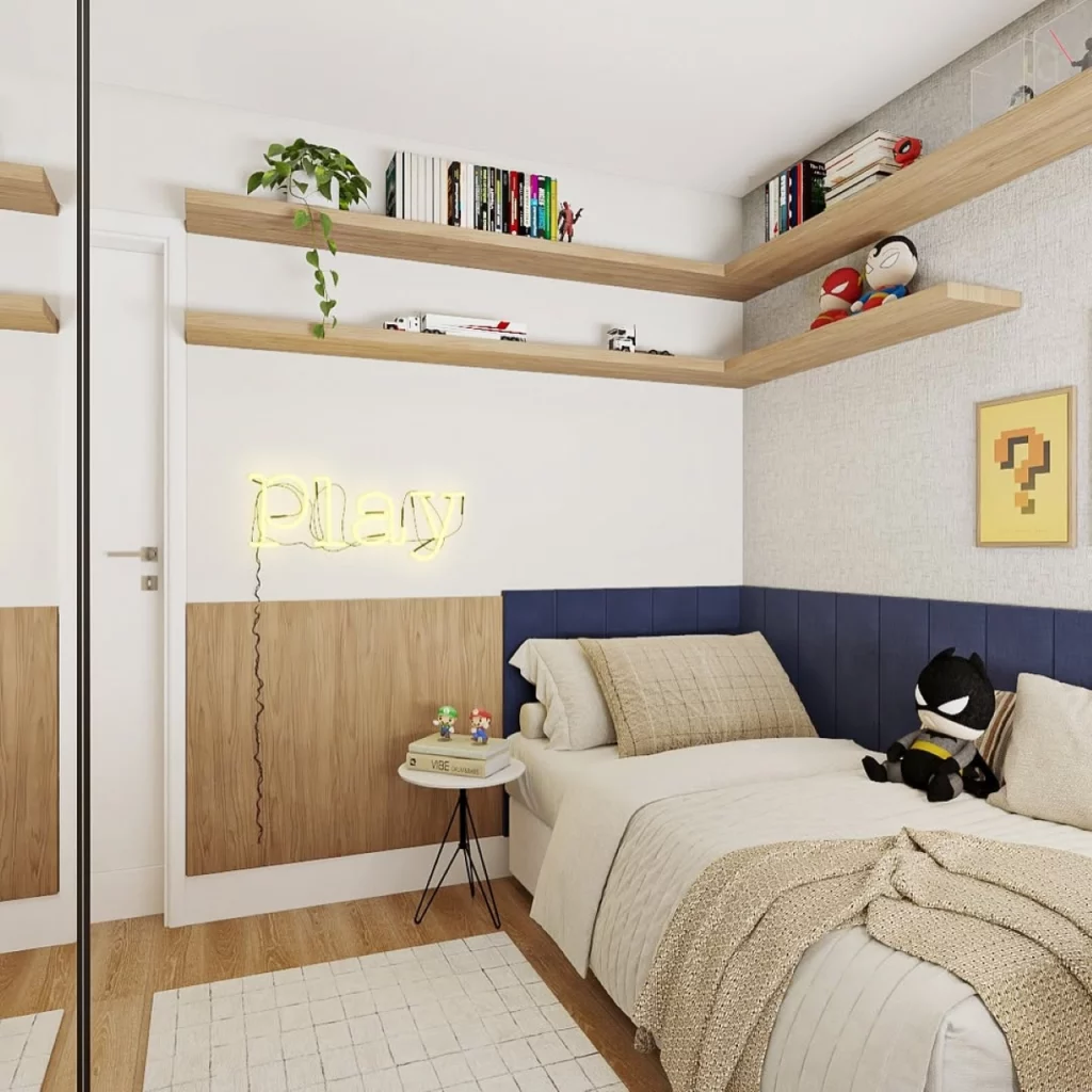 Quarto infantil de menino, com placa de neon, prateleiras na parede com livros e planta, quadro na parede, cama com almofada do Batman.