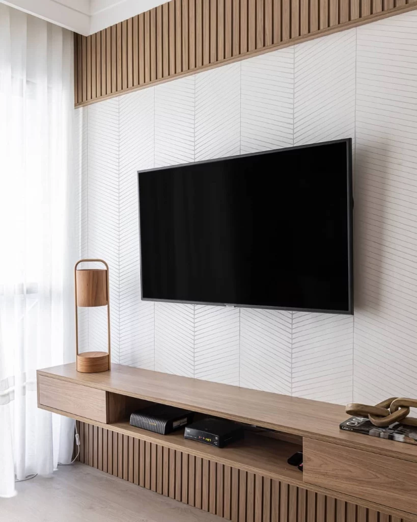 Sala de televisão com ripado e papel de parede na parede, estilo minamilista e discreto.