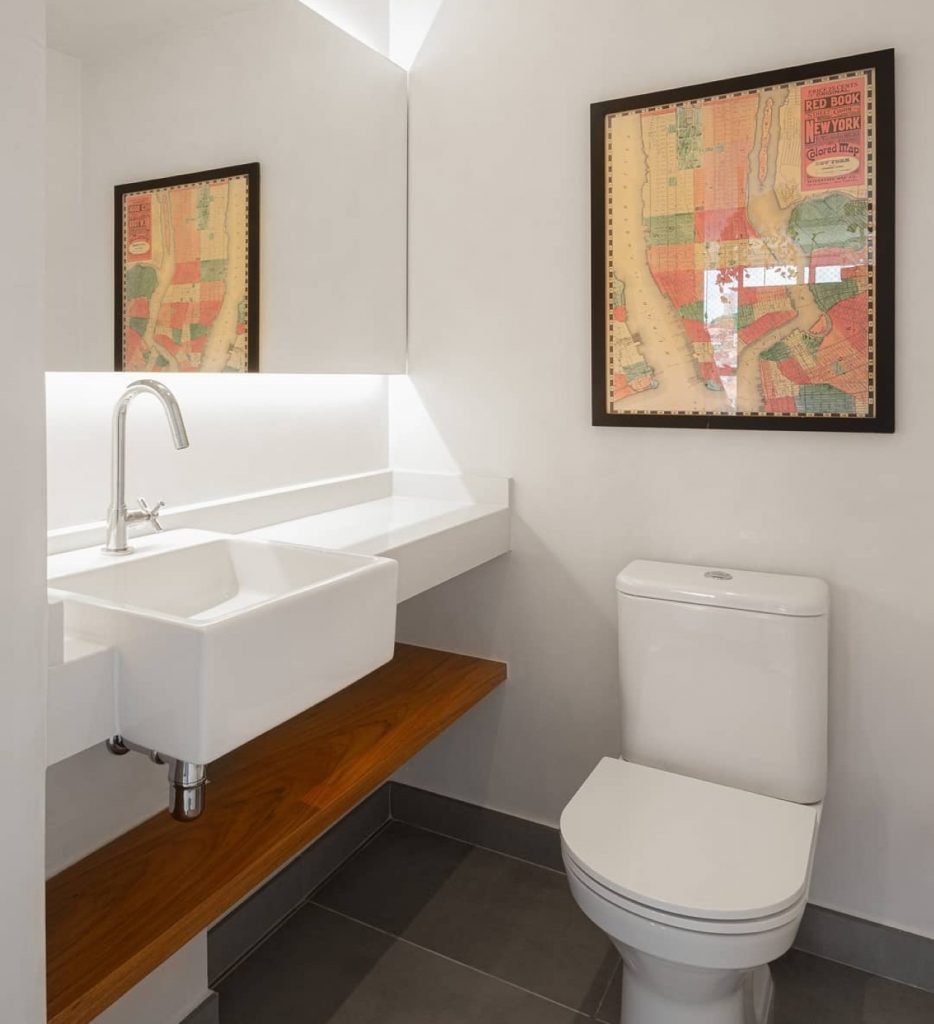 Lavabo branco e moderno com um quadro pendurado acima da privada.