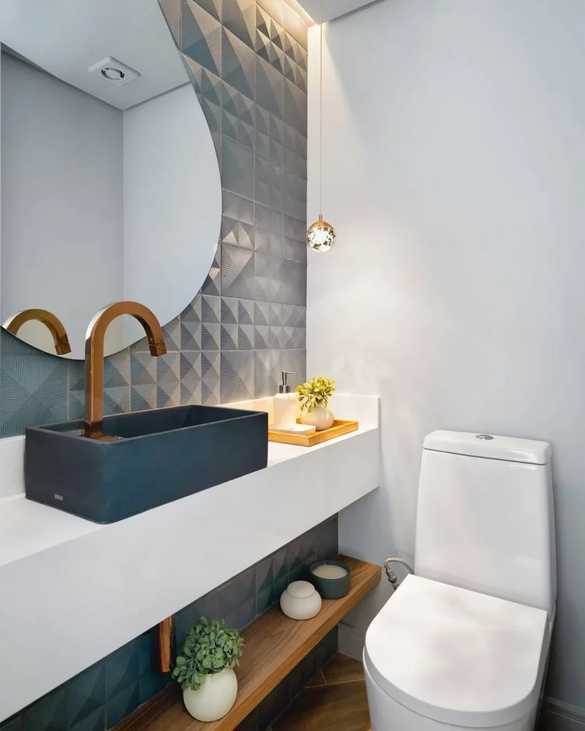 Banheiro com pia azul marinho, sem prateleiras, com espelho orgânico na parede com azulejos 3D.