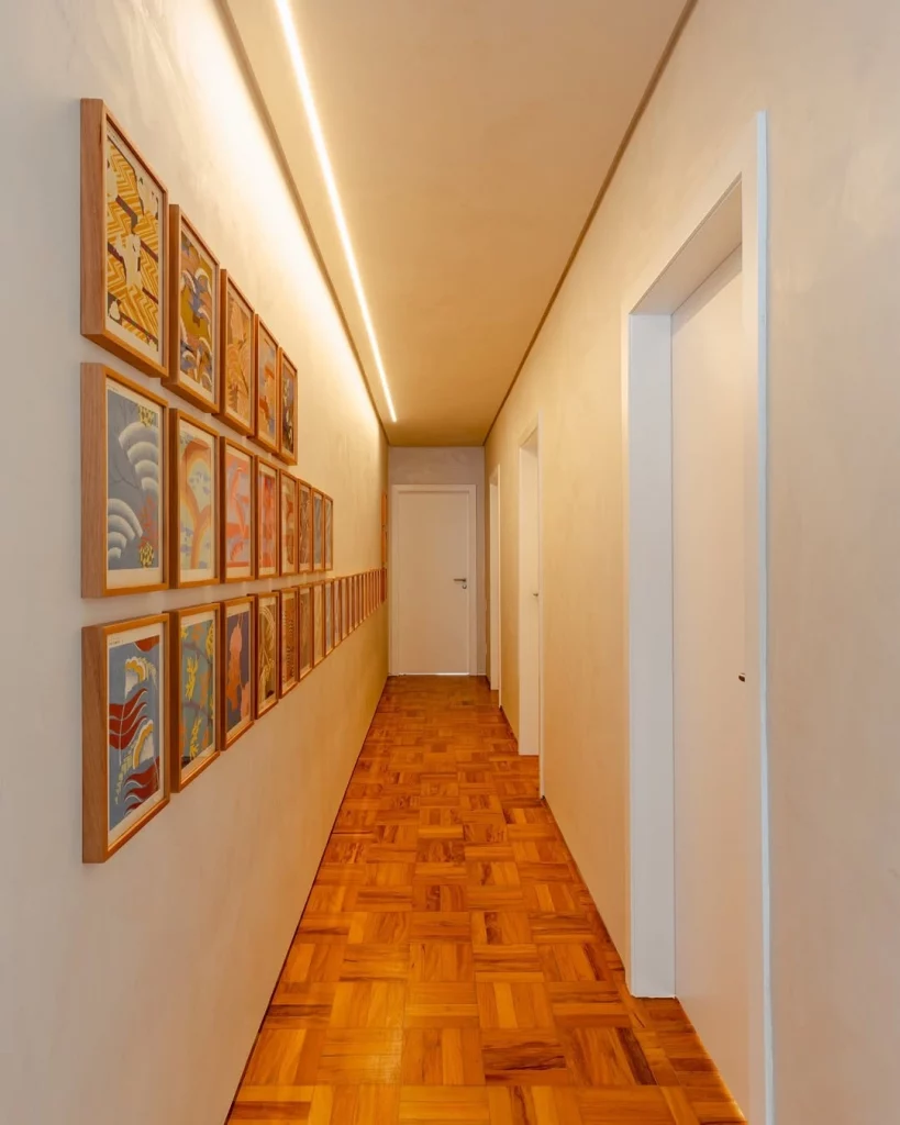 Corredor com galeria de quadros em três fileiras extensas.