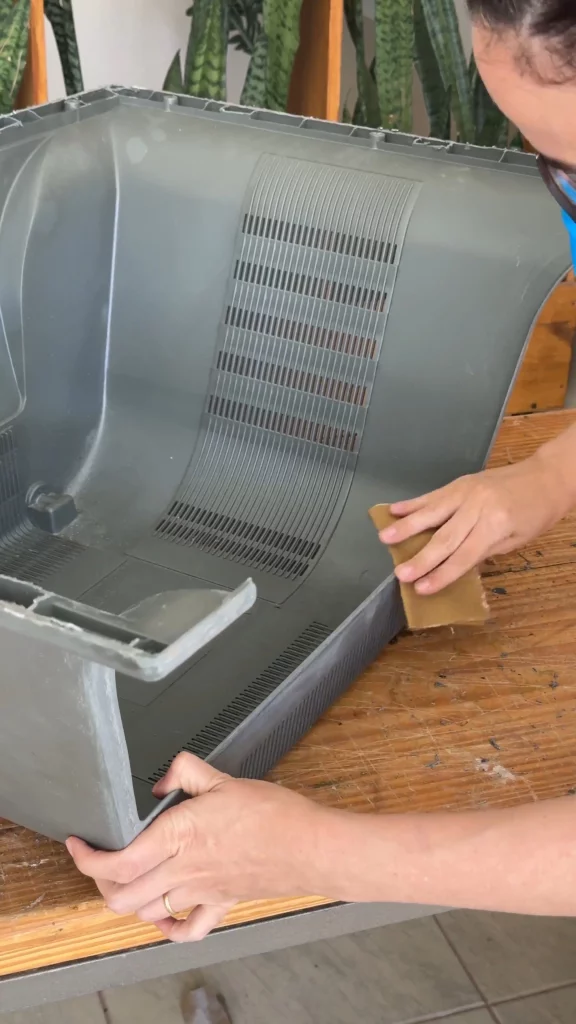 Lixando a carcaça de televisão com uma lixa.
