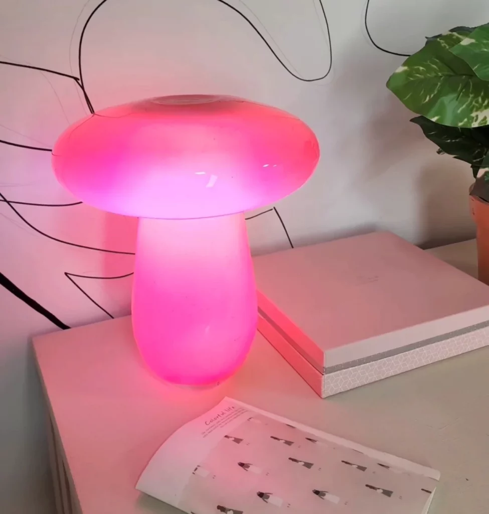 Luminária cogumelo rosa florescente na mesa.