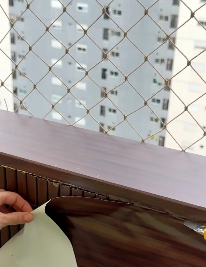 Instalando papel adesivo marrom escuro na mureta.