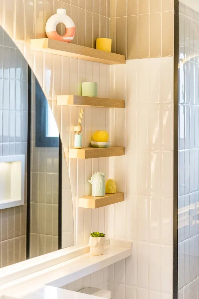 Prateleiras contornando o espelho, como uma espécie de escadinha, em diversos tamanhos e com utensílios e elementos decorativos.