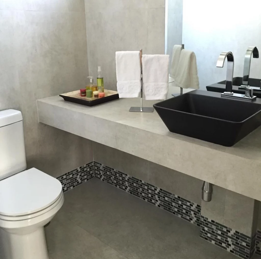 Banheiro sem armário com detalhes cinza e preto, suporte duplo na pia para toalhas.