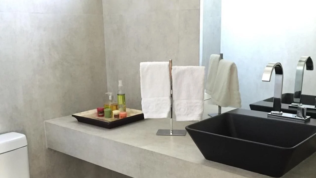 Banheiro sem armário com detalhes cinza e preto, suporte duplo na pia para toalhas.