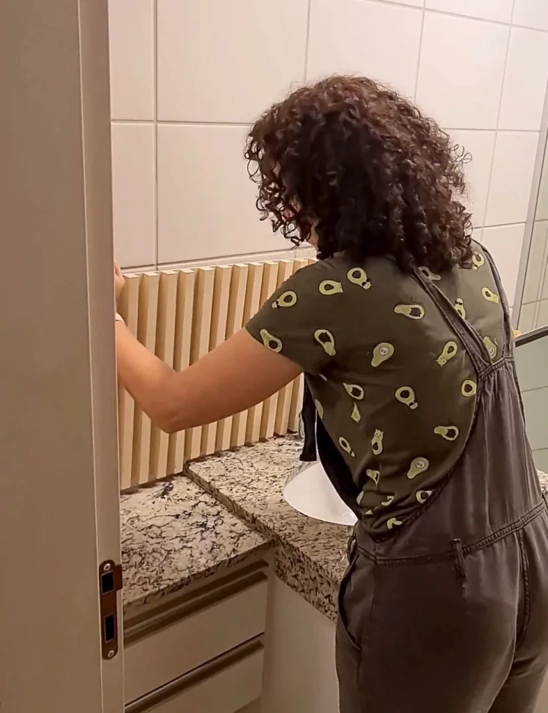 Painel ripado sendo colocado na parede do banheiro.