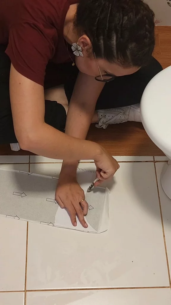 Moldando a curva do vaso sanitário para cortar o piso vinílico adesivo.