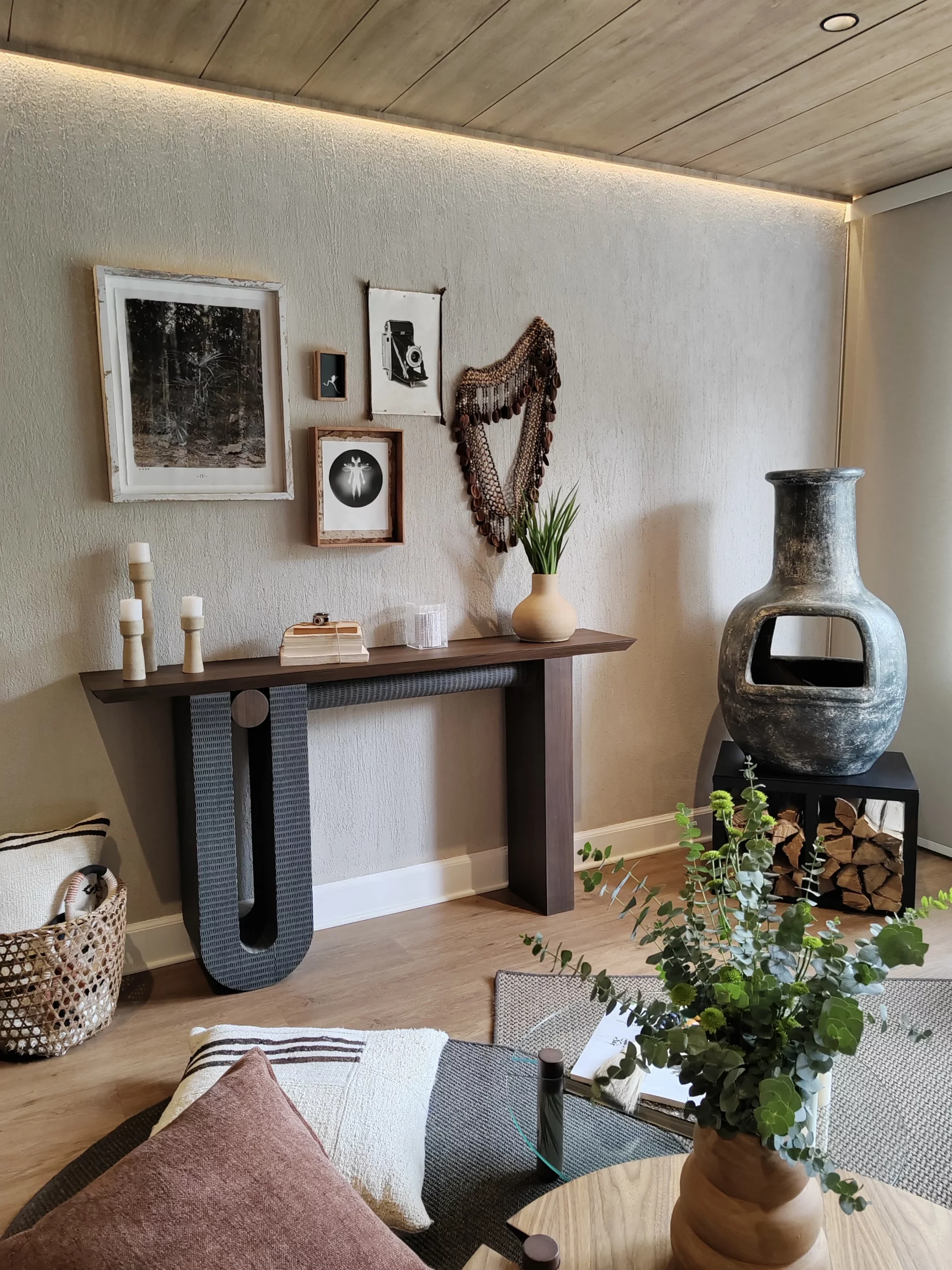 Sala com parede adornada por quadros e escultura de tecido em tom escuro.