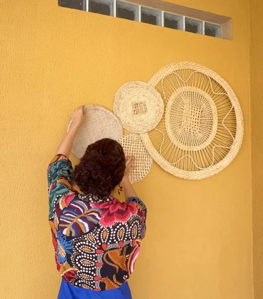 Instalando peneiras de palha na parede amarela.