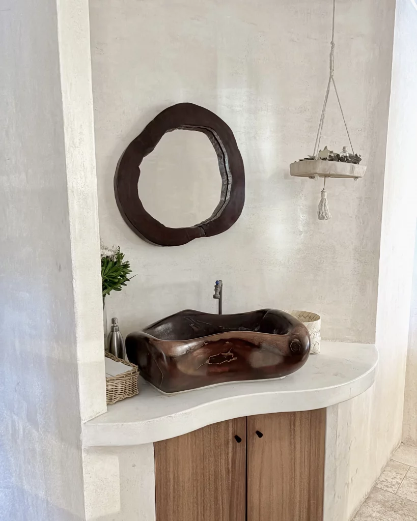 Lavabo branco com armário de madeira, espelho e cuba em marrom escuro.