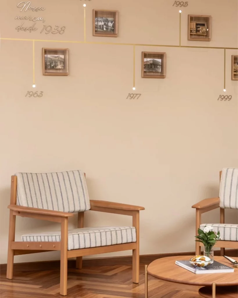 Galeria de fotos no fundo bege porcelana, com poltronas listradas e mesa de centro.