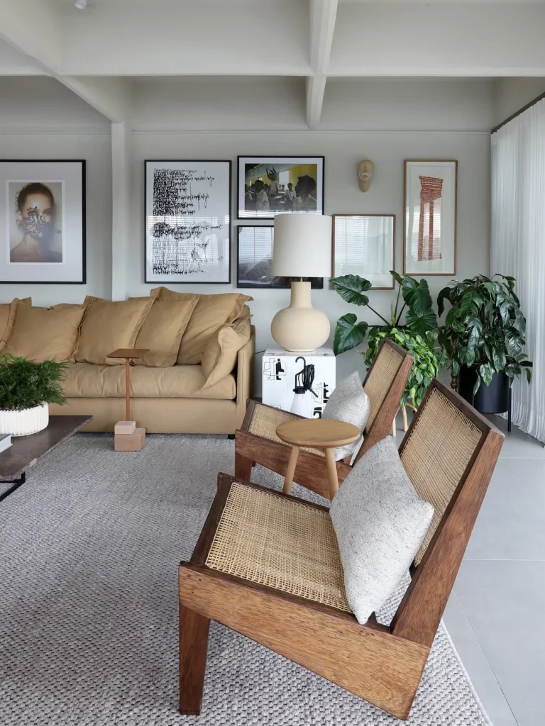 Sala de estar confortável com sofá bege e parede de quadros com fundo cinza claro.