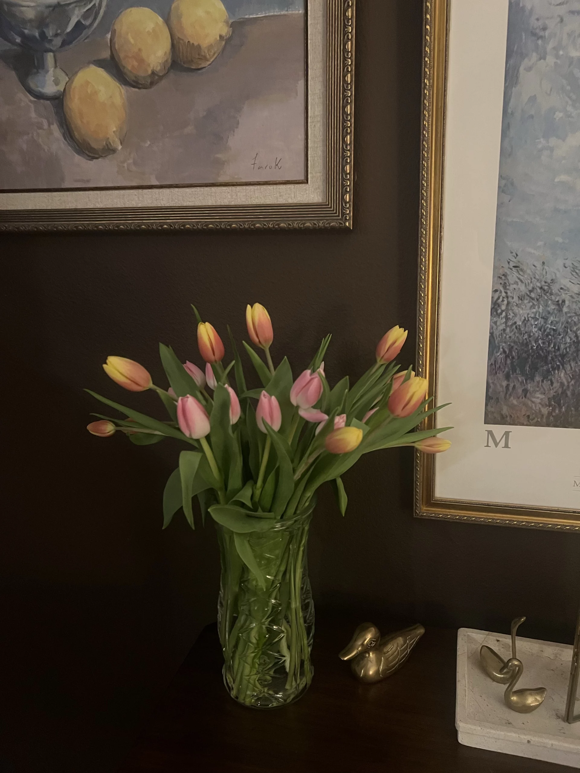 Fundo marrom com vaso de tulipas coloridas e quadros.