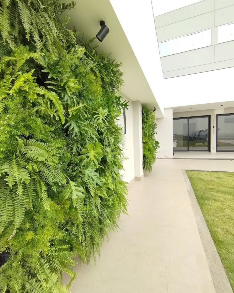 Parede verde na área externa de casa com porcelanato acetinado no chão.