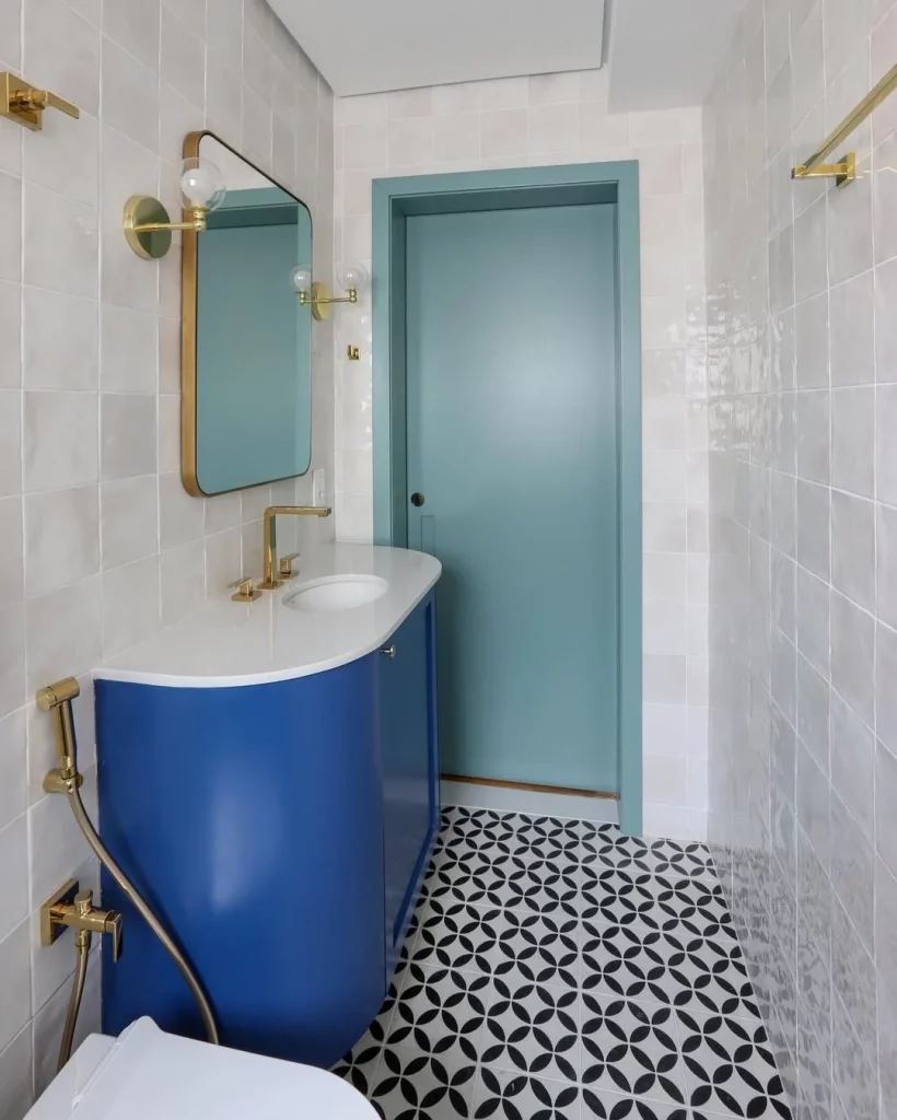Banheiro com armário azul e revestimento estampado de preto e branco no piso.