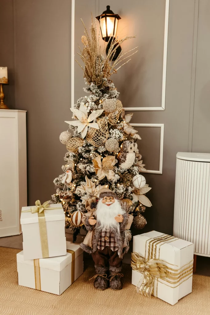 Árvore de natal pequena com papai noel grande e enfeites dourados.