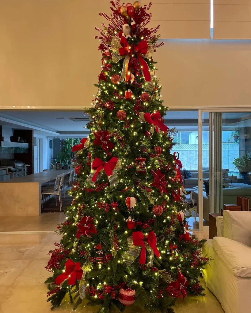 Árvore de natal elegante com poucos enfeites e laços vermelhos.