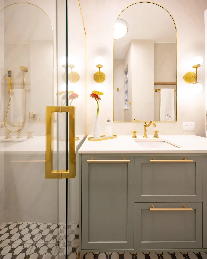 Banheiro clássico com elementos dourados e iluminação branca.