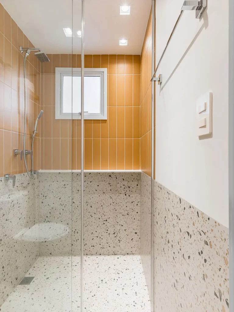 Parede com textura e revestimento no box laranja.