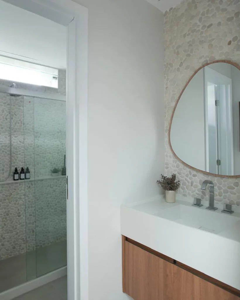 Banheiro de parede de pedra e espelho orgânico.