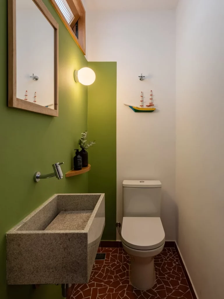 Banheiro com pintura verde na parede, barco de madeira no fundo e planta.