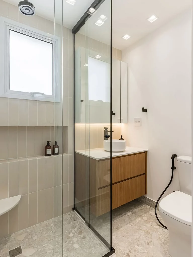 Banheiro minimalista com metais pretos e armário de madeira.