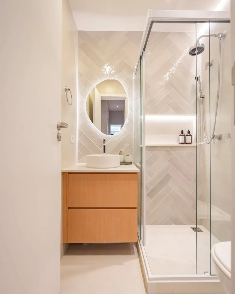 Banheiro minimalista com revestimento em triângulo e espelho iluminado.