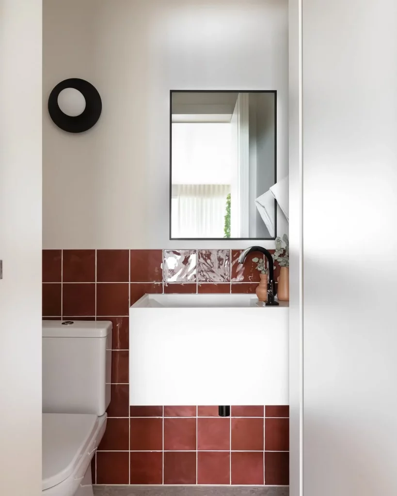 Banheiro com revestimento quadriculado e vermelho bordô.