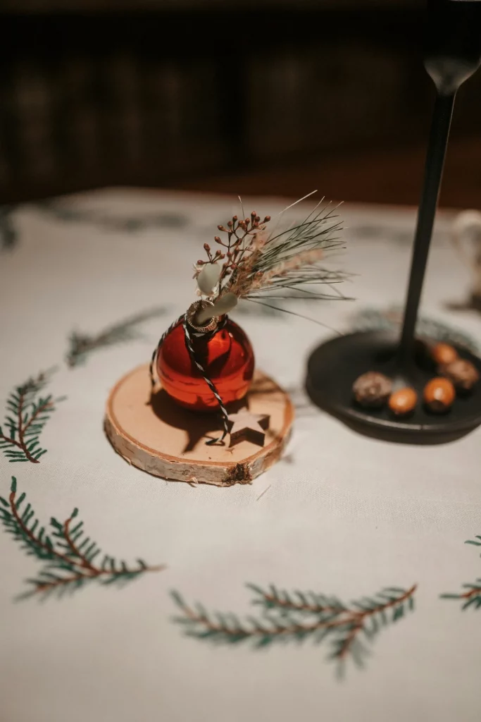 Bola de natal vermelha com galhos na mesa rústica com bolacha de madeira.