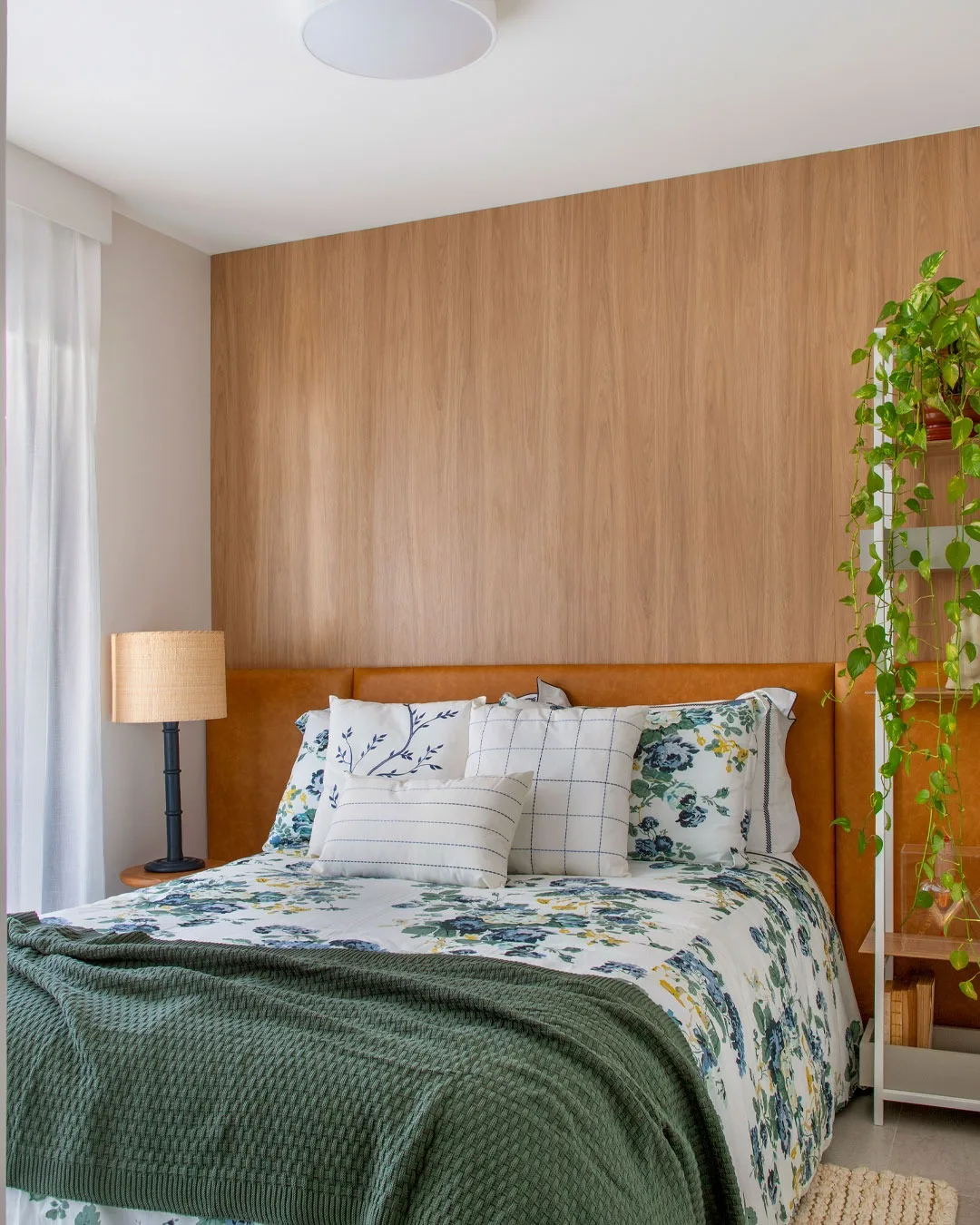Quarto alegre e vibrante com cabeceira marrom caramelo e roupa de cama floral.