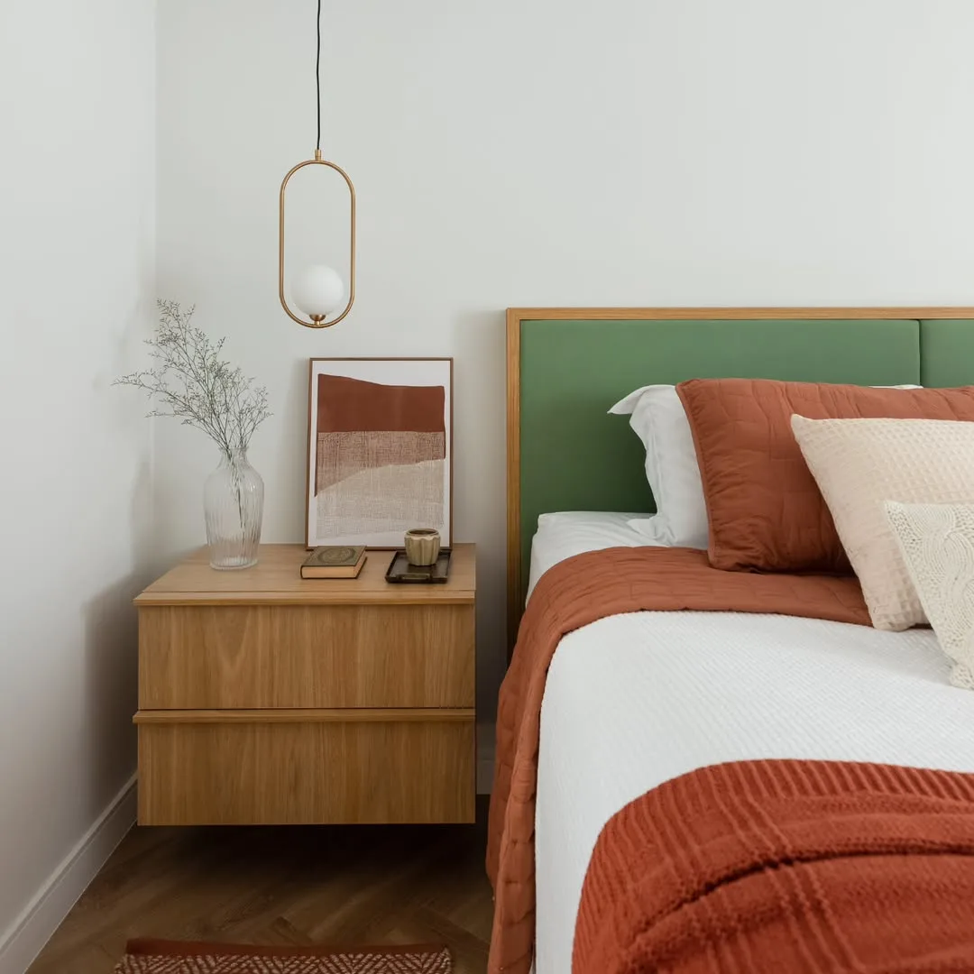 Cabeceira de quarto na cor verde com roupa de cama em tons terrosos e branco.