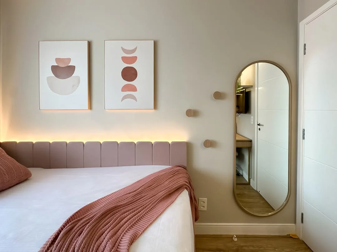 Cabeceira de cama rosa na lateral com iluminação amarela em cima.