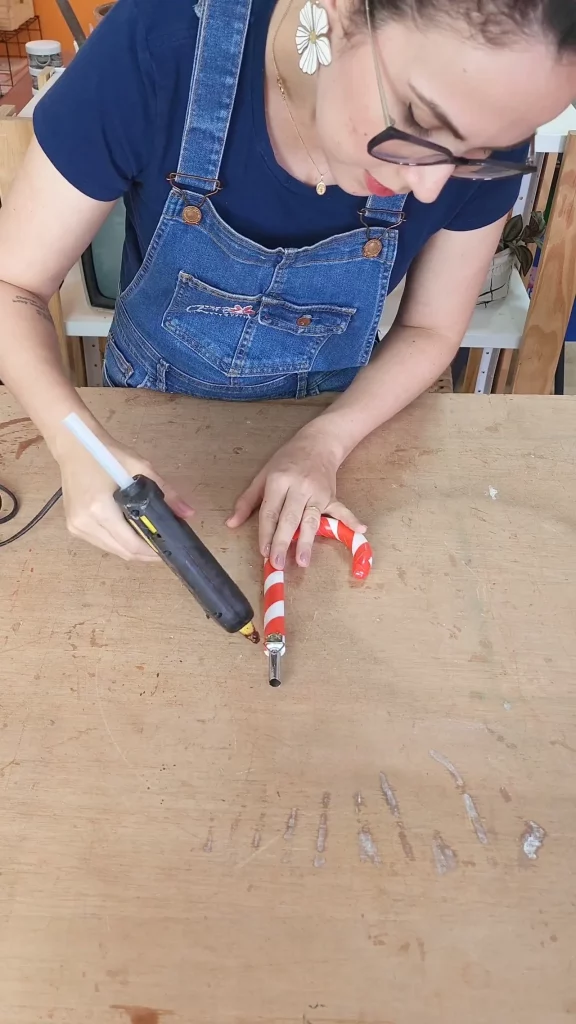 Colando com cola quente o gancho de pendurar quadro no cabo de guarda-chuva.