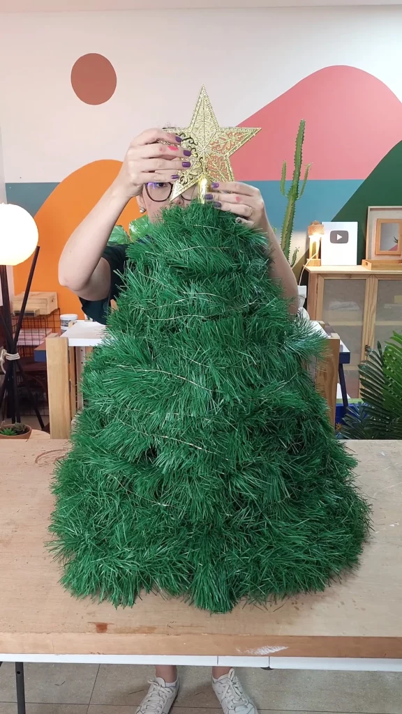Decorando a árvore de natal com uma etsrela e fio de fada.