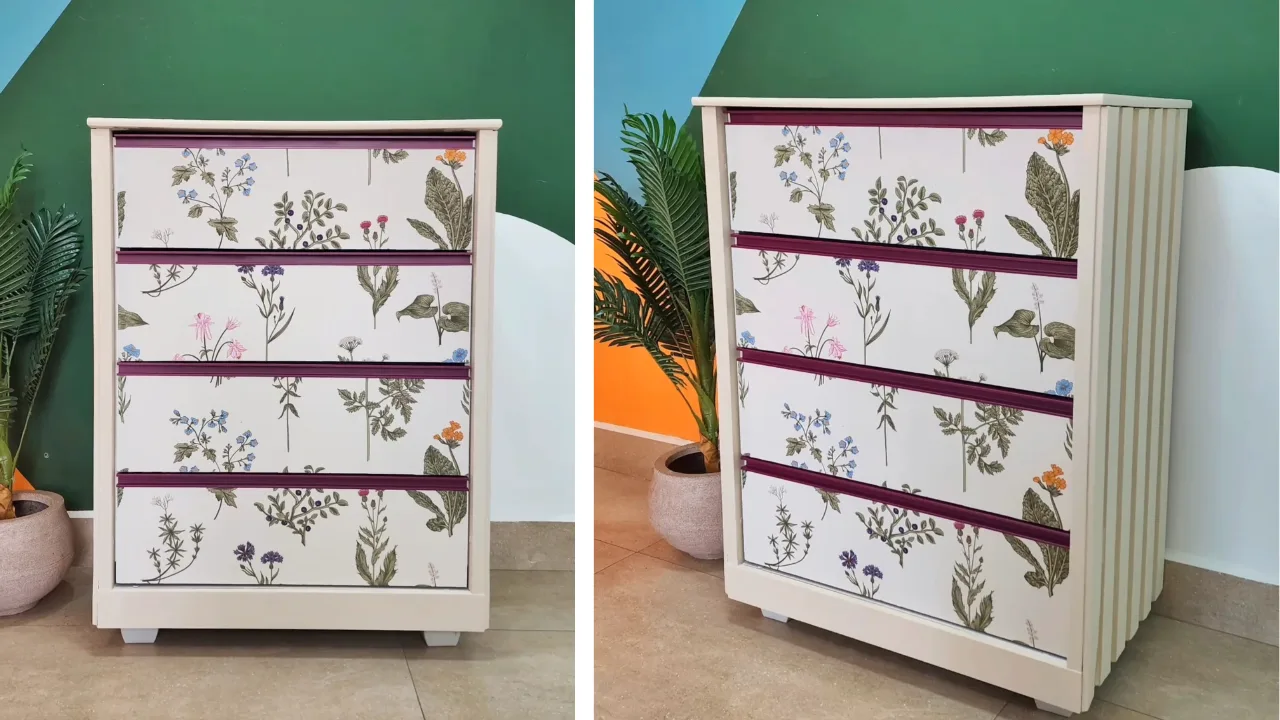 Cômoda antiga transformada, pintada de bege claro, com puxadores magenta e papel de parede floral na gaveta.