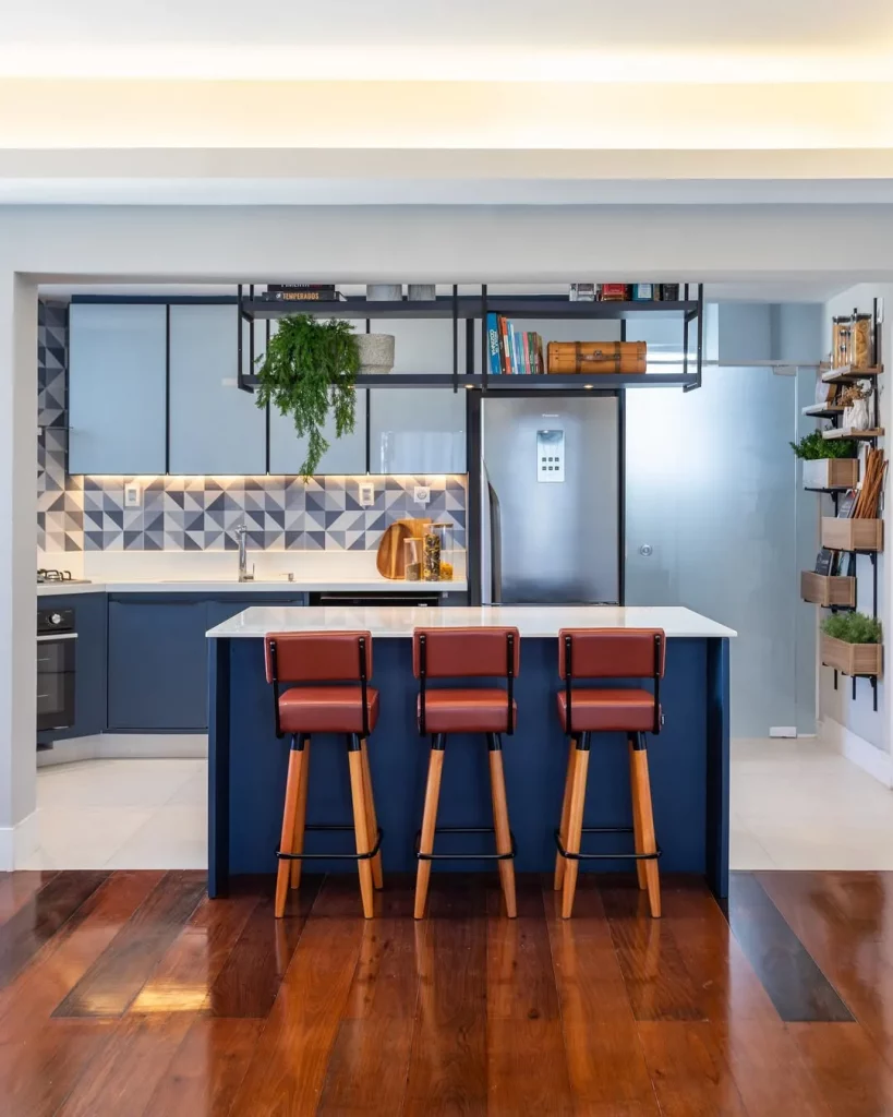 Cozinha americana com balcão azul e banquetas de couro com metal preto.