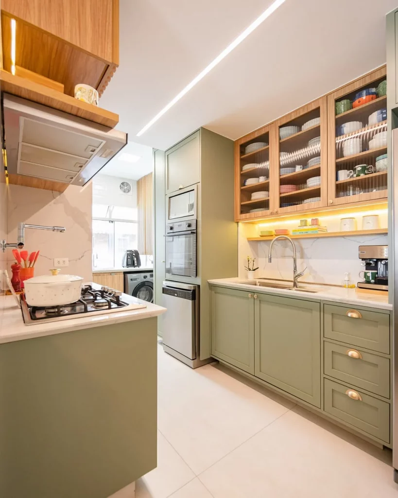 Cozinha com armários verdes e clássicos, iluminados com LED amarelo e piso de porcelanato acetinado fosco.