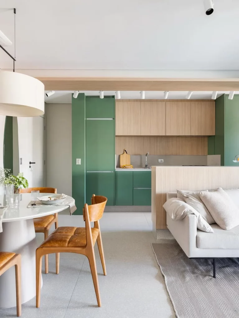 Sala de estar e jantar conjugada com cozinha de armários verde e de madeira.