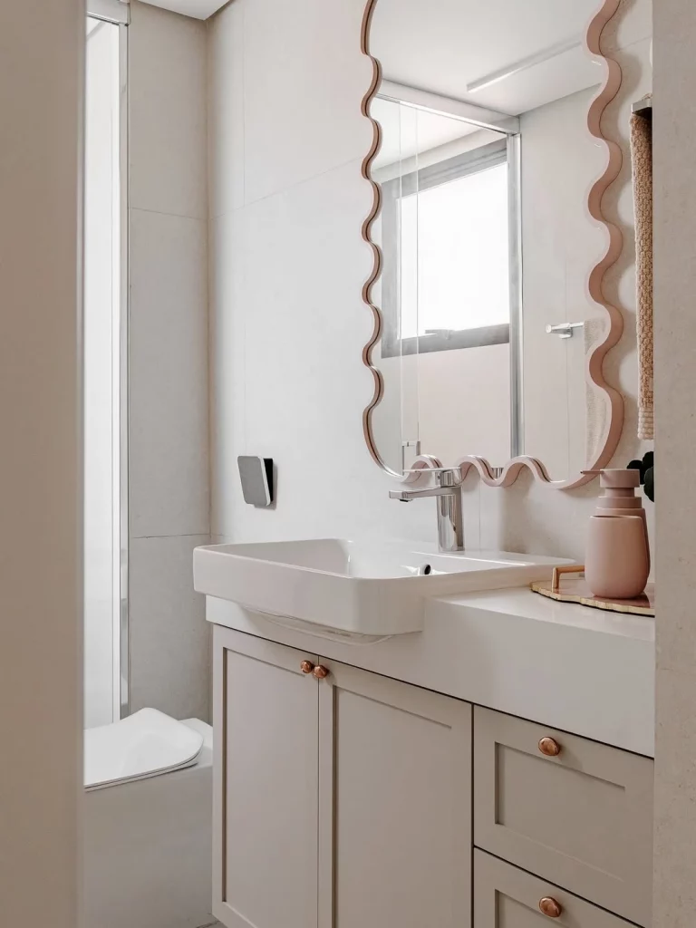 Espelho com design ondulado e moldura rosa na parede.