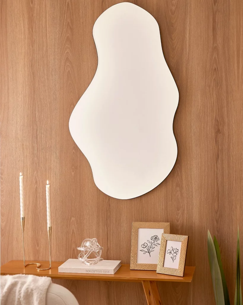 Espelho sem moldura no fundo de madeira e formato orgânico.
