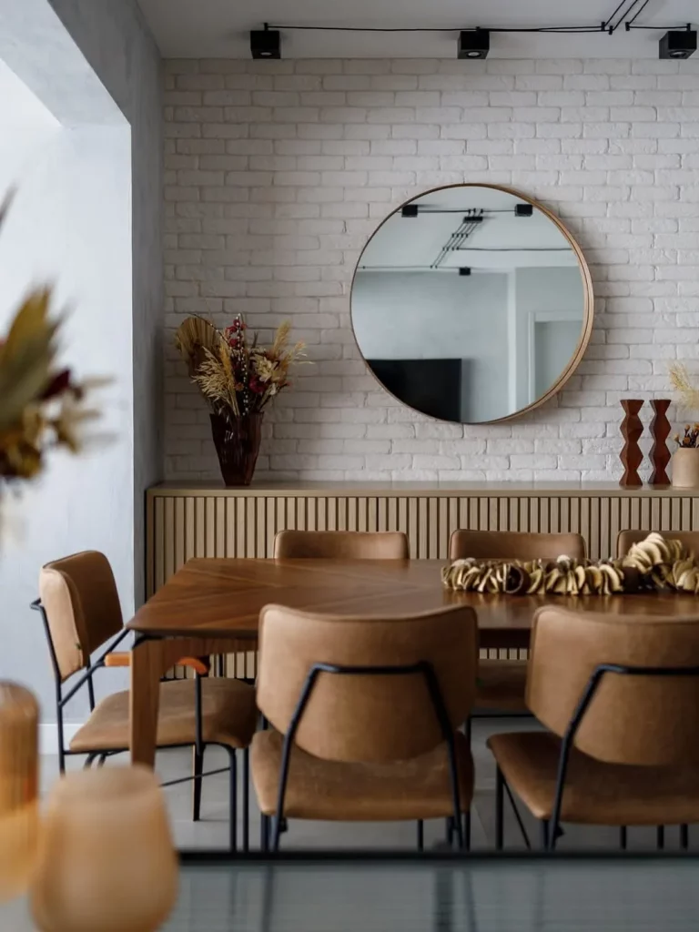 Espelho redondo grande perto do aparador na sala de jantar.