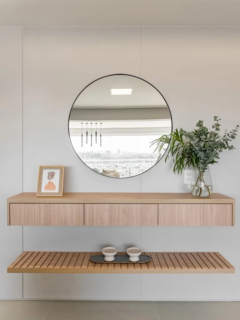 Espelho redondo pendurado acima do aparador da sala de estar com planta.