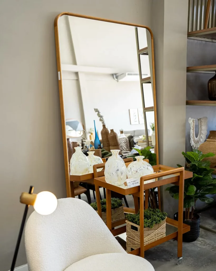 Espelho apoiado na parede perto do carrinho-bar.