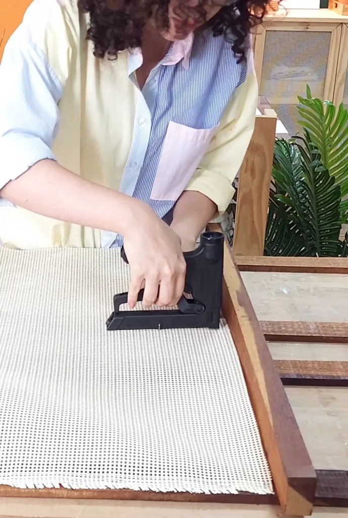 Grampeando a talagarça na parte traseira do estrado de cama.